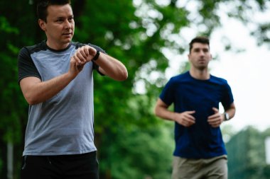 Gençler yarış pistinde antrenman yapıyor. İki genç arkadaş atletizm pistinde koşuyor.