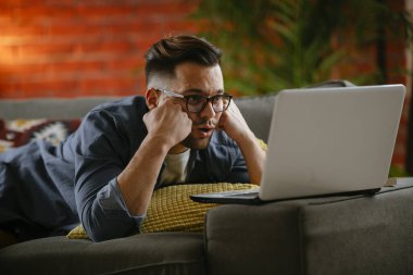 Evdeki dizüstü bilgisayarda dizi izleyen bir adam..