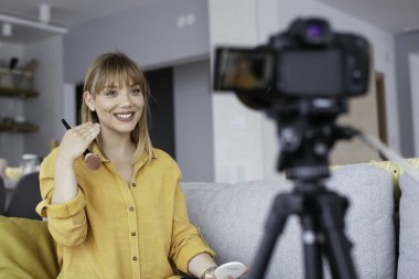 Kadın video kaydedicisi, kanalı için makyaj dersi kaydediyor. Sosyal medyada paylaşmak için makyaj dersi alan genç ve güzel bir kadın..