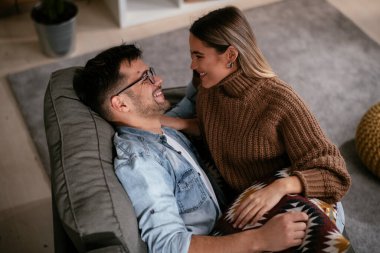 Genç adam ve kız arkadaşı oturma odasında kanepede.