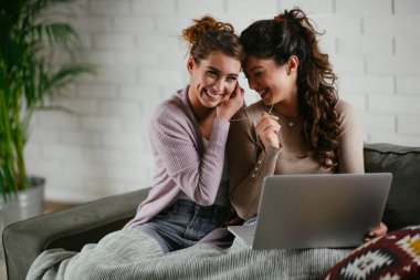 Kız arkadaşlar evde dizüstü bilgisayardan müzik dinlerler. Kızlar apartmanda eğleniyor..