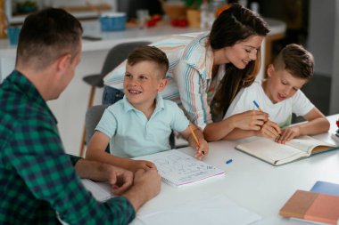 Anne ve baba oğullarına ev ödevlerinde yardım ederler.