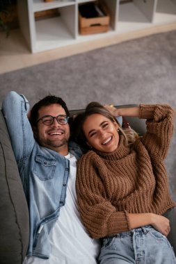 Genç adam ve kız arkadaşı oturma odasında kanepede.
