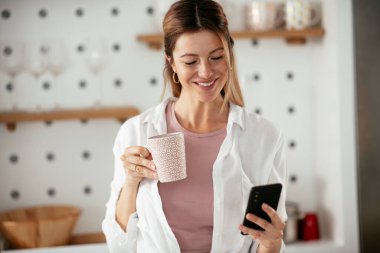 Mutfaktaki kadın. Mutfakta telefon kullanan güzel bir kadın..