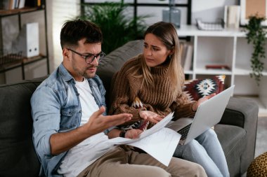 Genç adam ve kız arkadaşı kanepede kağıtlarla.