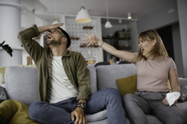 Erkek arkadaşı ve kız arkadaşı kanepede tartışıyor. Kızgın kadın erkek arkadaşına bağırıyor..