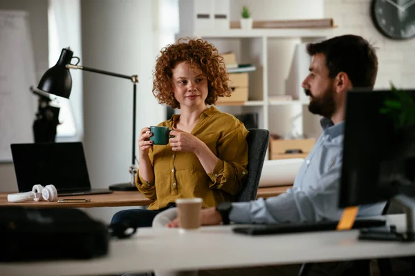 Business people in office. Businesswoman and businessman discussing work while drinking coffee.