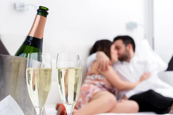 Champagne glasses with kissing couple in background — Stock Photo, Image