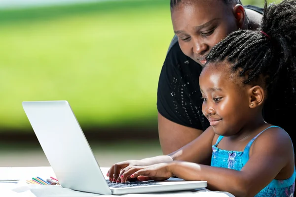 Afrikanische Mutter hilft Kind am Laptop. — Stockfoto