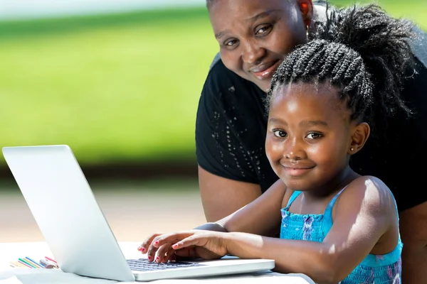 Söt afrikansk flicka och mamma med laptop. — Stockfoto