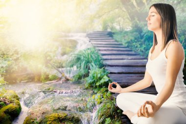 Girl meditating next to stream in forest. clipart