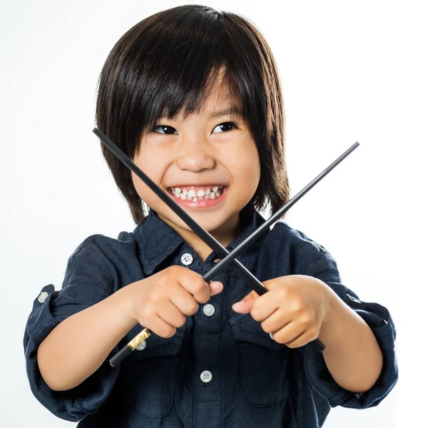 Liten asiatisk pojke leker med ätpinnar. — Stockfoto