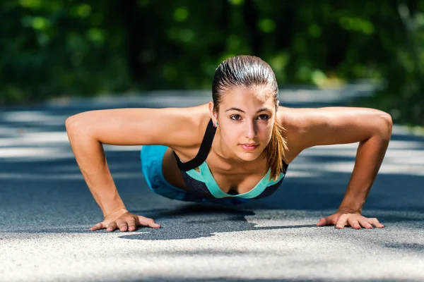 Žena, která dělá push up na tar road. — Stock fotografie