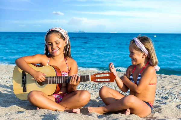 Девушки с гитарой на пляже — стоковое фото