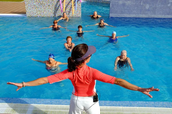 Vattengymnastik instruktör gör seniorklassen i poolen. — Stockfoto