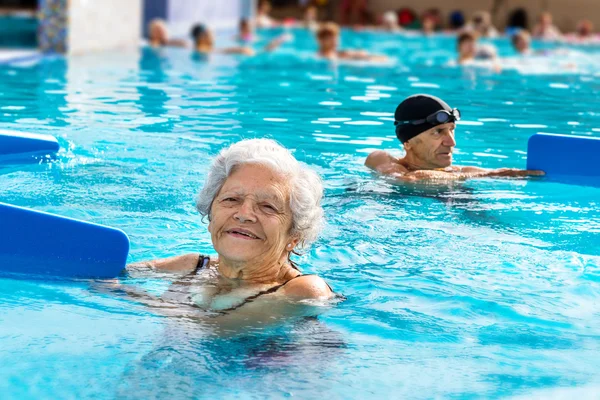 Senior vrouw tijdens aquagym zitting. — Stockfoto