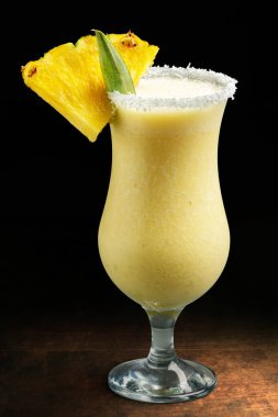 Siyah arka planda serinletici sarı pina colada meyve kokteylini kapat.