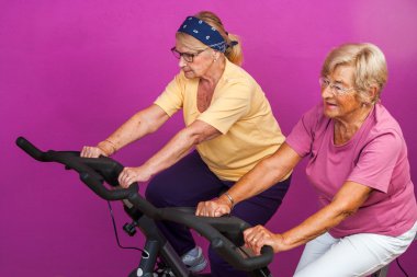 Elderly women doing leg exercises in gym. clipart