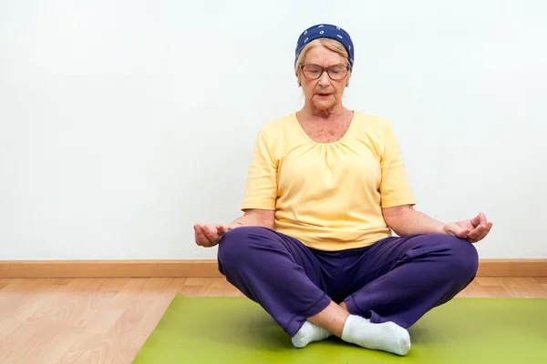 Äldre kvinna utövar yoga i gym. — Stockfoto