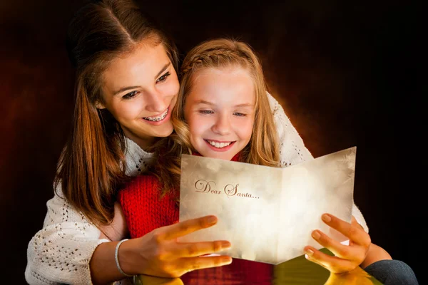 Menina lendo cartão de Natal para irmã . — Fotografia de Stock