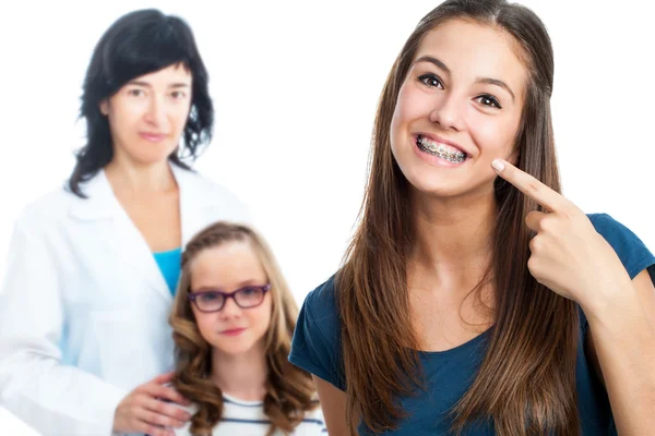 Ragazza adolescente che indica le chiatte dentali con il medico in background . — Foto Stock