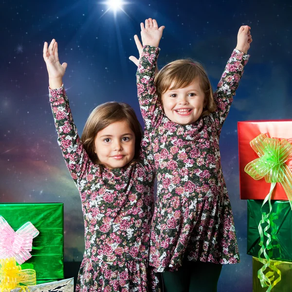 Dos niños felices levantando las manos junto a los regalos . — Foto de Stock