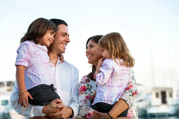 Pareja joven sosteniendo a sus hijos en brazos al aire libre . — Foto de Stock