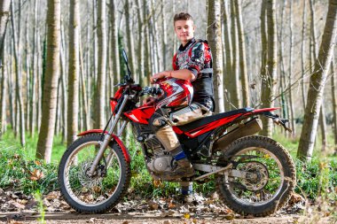 Yakışıklı genç çocuk motokros motosiklet üzerinde oturan.