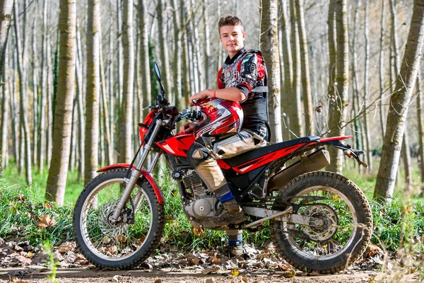 Knappe tiener jongen zittend op motorcross motor. — Stockfoto