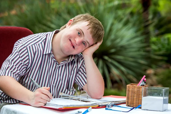 Behinderter Junge ruht auf Schreibtisch. — Stockfoto