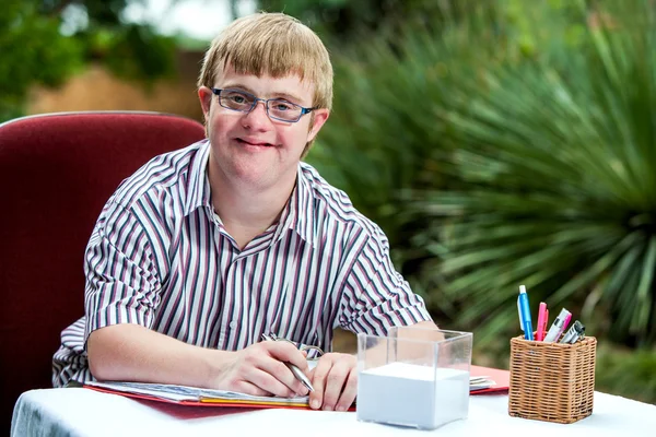 Handicapped boy at desk in garden. — Stock Photo, Image