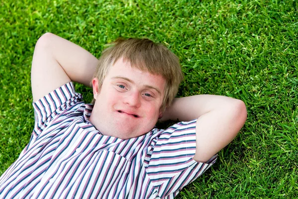 Gehandicapte jongen ontspannen op groen gras. — Stockfoto