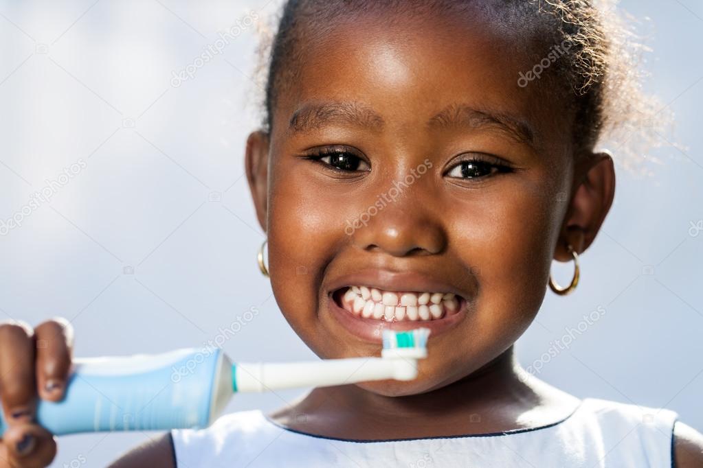Cute little afro girl holding electric toothbrush.