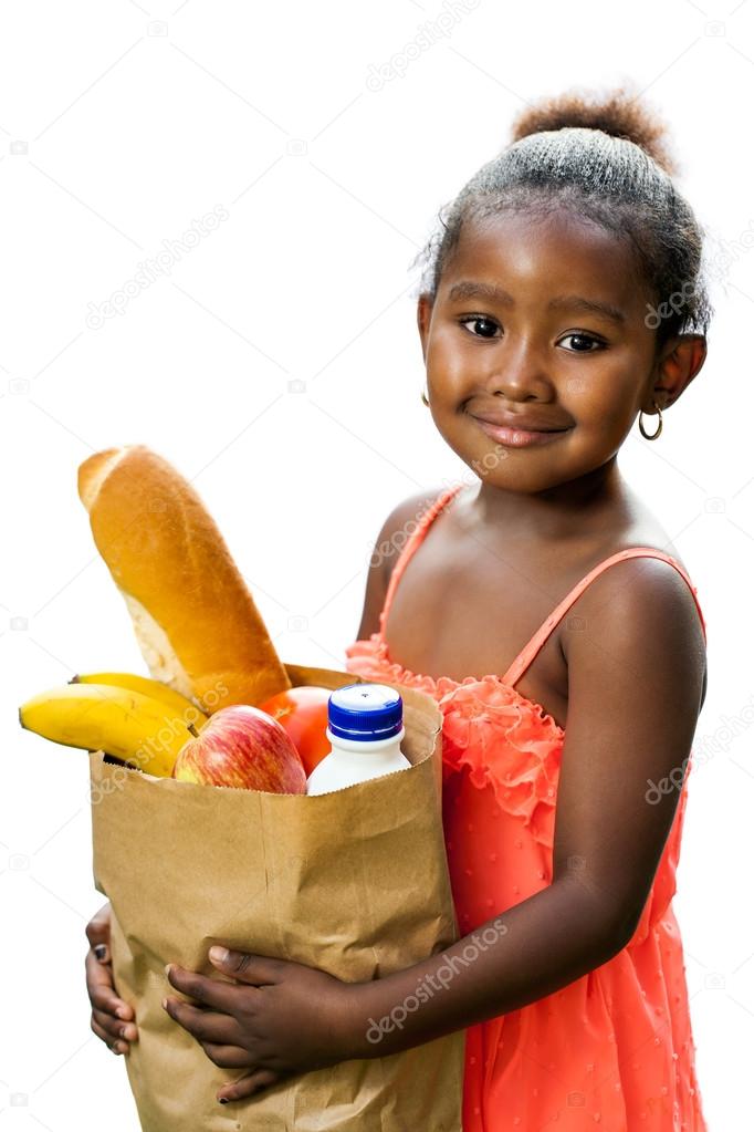Cute african kid holding groceries in brown bag.