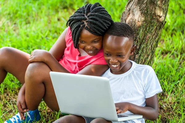 Afrikansk pojke och flicka som leker på laptop. — Stockfoto