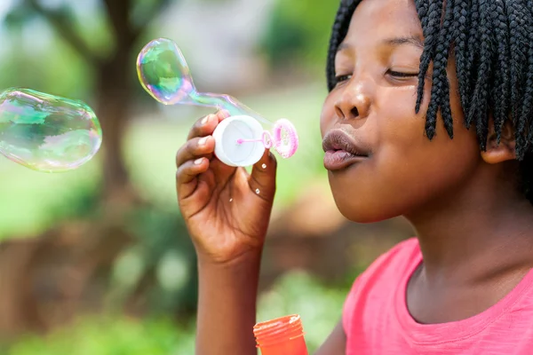 African girl with braids blowing bubbles. — Stock Photo, Image