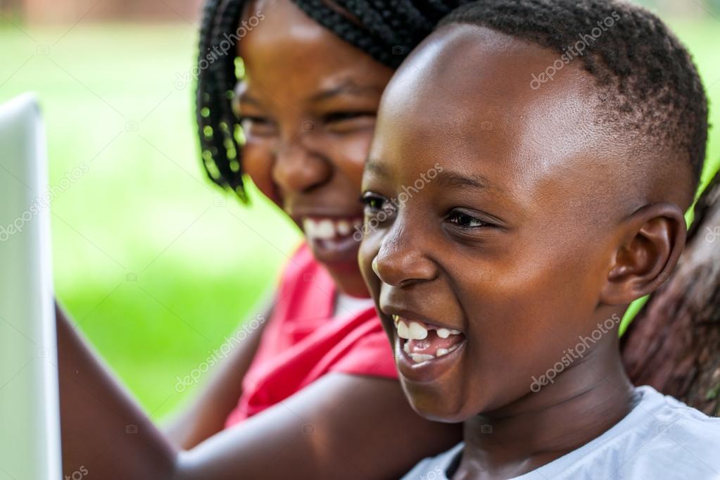 Laughing African kids looking at laptop screen. Stock Photo by