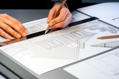 Mimari belgeler üzerinde çalışan eller.