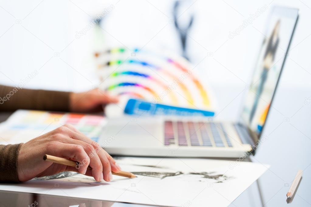 Designer hand making sketch with color chart.
