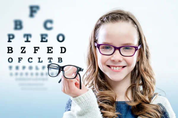 Girl holding glasses with test chart in background. Royalty Free Stock Photos