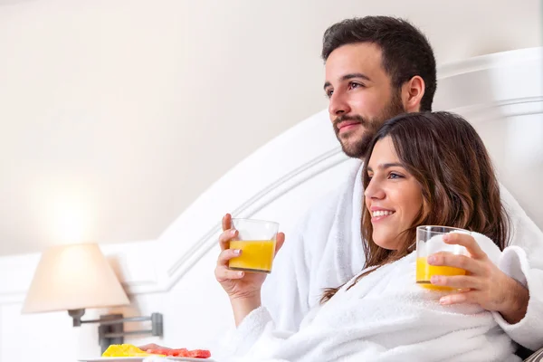 Paar im Bademantel trinkt Orangensaft. — Stockfoto