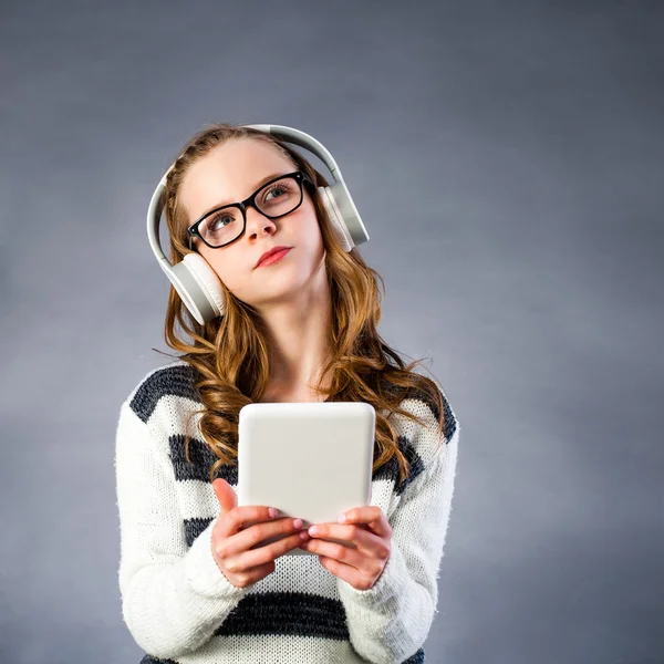 Menina bonito com fones de cabeça segurando tablet . — Fotografia de Stock