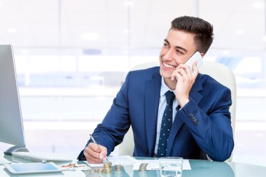 İşadamı ofiste akıllı telefondan konuşuyor.