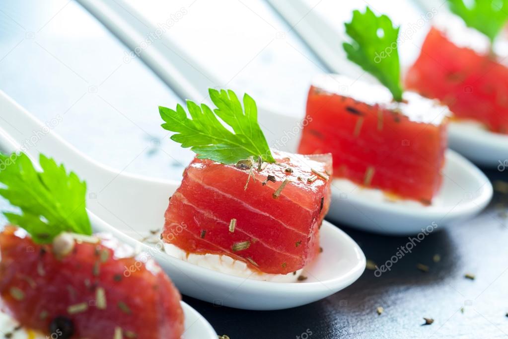 Appetizing tuna morsel on ceramic spoons.