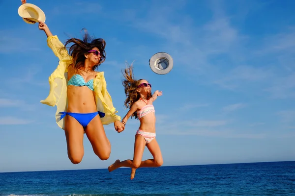 Happy girls jumping together on beach. — Stock Photo, Image