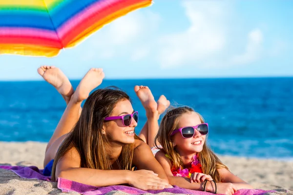 Twee jonge meisjes samen liggend op strand. — Stockfoto
