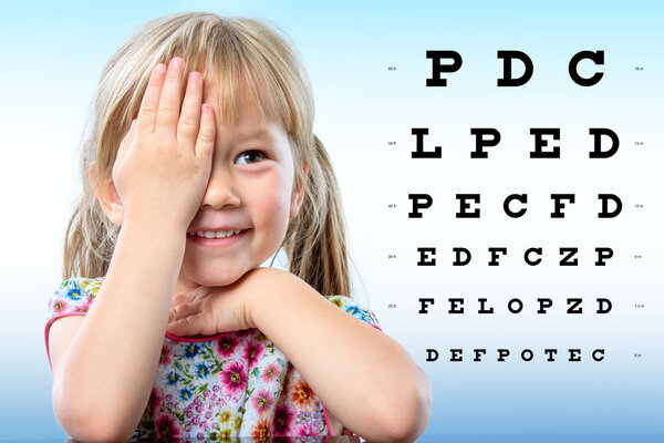 Cute little girl reviewing eyesight on chart.