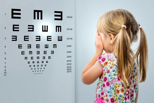 Menina olhando para gráfico de teste de visão . — Fotografia de Stock