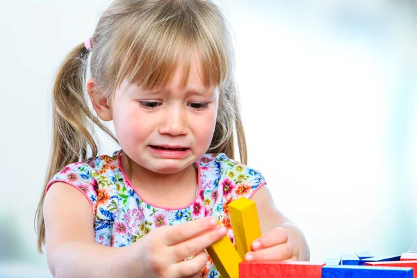 Unhappy little girl playing with wooden blocks. — Stock Photo, Image
