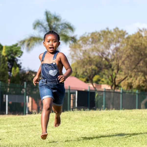 สาวแอฟริกันตัวน้อยวิ่งในสวนสาธารณะ — ภาพถ่ายสต็อก